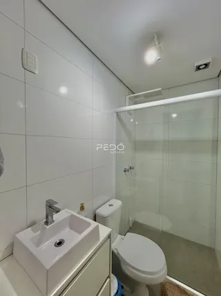 Banheiro moderno com revestimento cerâmico branco.