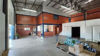 Espaço amplo com estrutura de tijolos aparentes e teto metálico em um imóvel comercial.