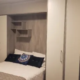 Quarto com cama e prateleiras de madeira instaladas.
