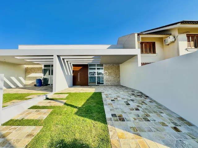 Fachada de uma casa moderna em Lajeado, Brasil, com jardim e área externa pavimentada.
