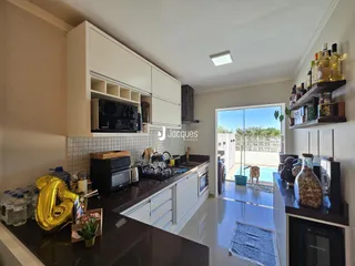 Cozinha moderna com armários brancos e bancadas escuras, com vista para uma área externa.