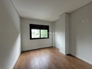 Sala de estar com piso de madeira e parede branca.