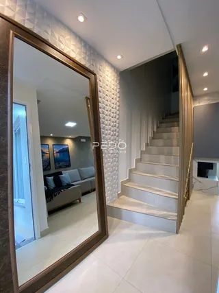 Hall de entrada com espelho e escadaria em um imóvel.