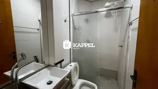 Banheiro com box de vidro, pia e vaso sanitário brancos.