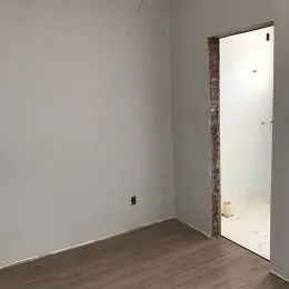 Parede branca e piso de madeira em um ambiente interno.