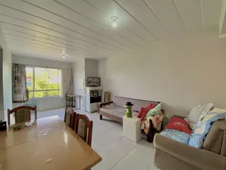 Sala de estar com sofá e mesa de madeira em ambiente claro.
