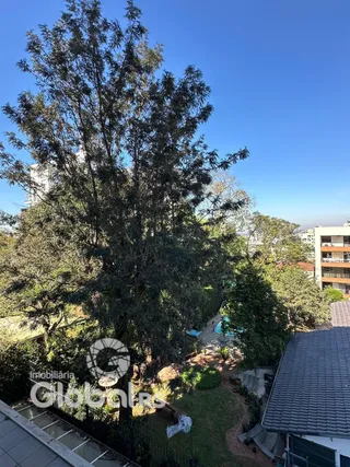 Vista externa de uma propriedade com vegetação densa e telhado.