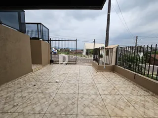 Área externa pavimentada com piso de cerâmica e portão de ferro.