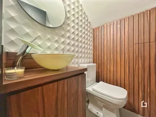 Foto de um banheiro com bancada de madeira e revestimento branco.