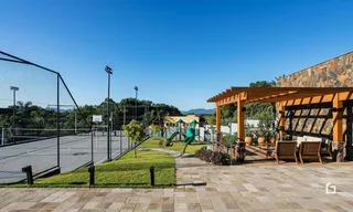 Vista externa de uma área de lazer com gramado e estrutura de madeira.