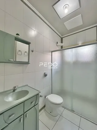 Foto de um banheiro com revestimento branco e box de vidro transparente.