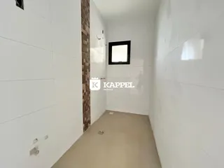 Hall de entrada com paredes brancas e piso claro.