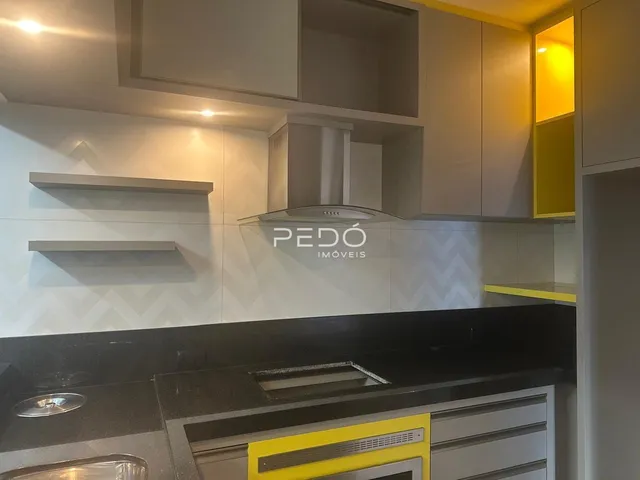 Cozinha moderna com armários brancos e bancadas escuras.