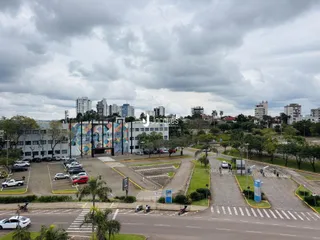 Vista externa de uma propriedade com estacionamento e área verde.