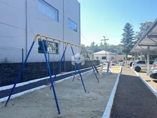Área externa com playground e cerca em um lote residencial.