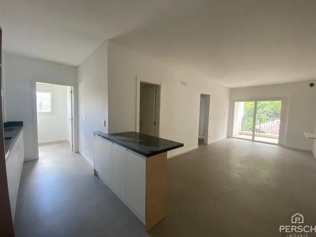 Sala de estar com bancada de cozinha e porta de vidro que dá acesso ao exterior.