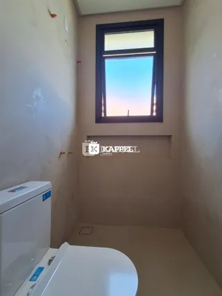 Foto interna de um banheiro com um vaso sanitário e uma janela.