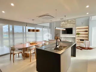 Ambiente de sala de jantar e cozinha moderna com vista para o mar.