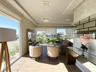 Sala de estar com piso de madeira e grandes janelas que dão vista para o exterior.