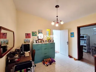 Sala de estar com armário verde e área de trabalho.