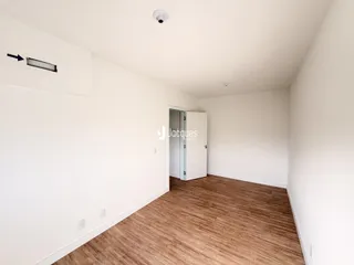 Vista interna de um cômodo com piso de madeira clara e paredes brancas.