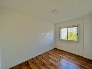 Ambiente interno de uma sala com piso de madeira e paredes brancas.
