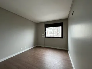 Uma sala de estar com piso de madeira e vista urbana através da janela.