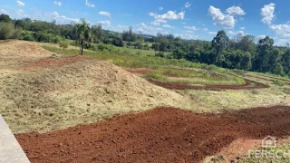 Paisagem de terra vermelha com vegetação verde ao fundo.