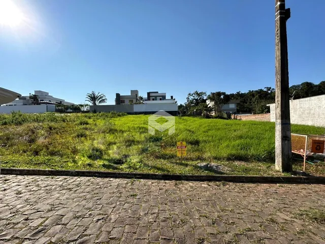 Vista externa de um terreno com gramado verde e uma cerca de pedra.