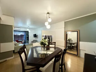 Uma sala de jantar com mesa de madeira escura e espelhos decorativos.