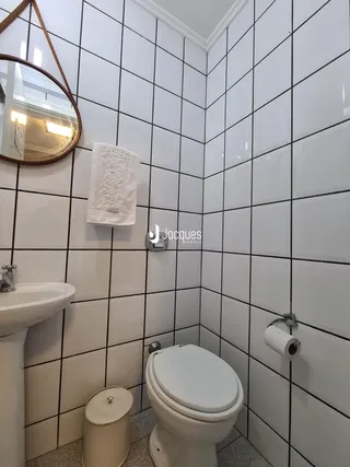 Foto de um banheiro com revestimento de azulejos brancos.