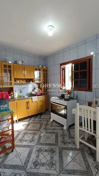 Foto interna de uma cozinha com armários amarelos e piso de cerâmica na Lajeado.