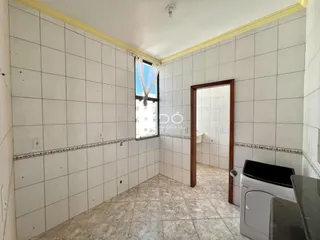 Interior de um corredor com paredes de azulejo branco e piso claro.