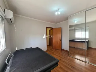 Quarto com piso de madeira e espelho na sala.