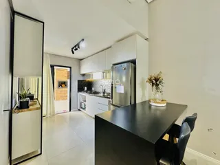 Vista da cozinha moderna com armários brancos e bancadas escuras.