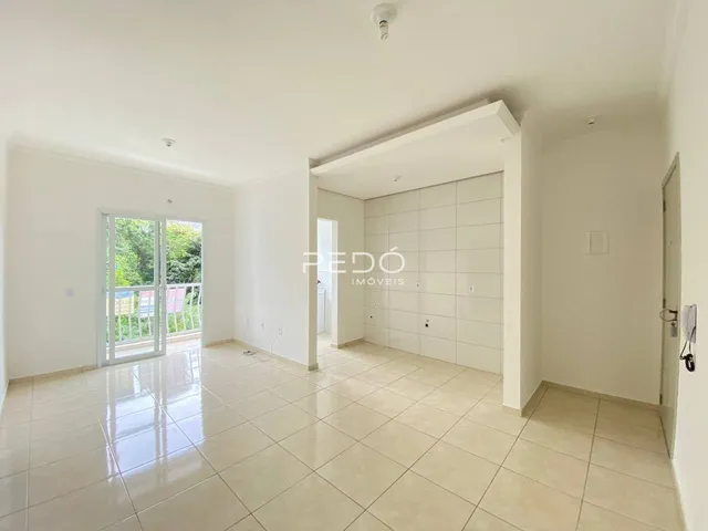 Sala de estar com piso de cerâmica clara e porta de vidro abrindo para o exterior.