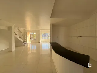 Um corredor amplo e iluminado com piso claro e paredes brancas.