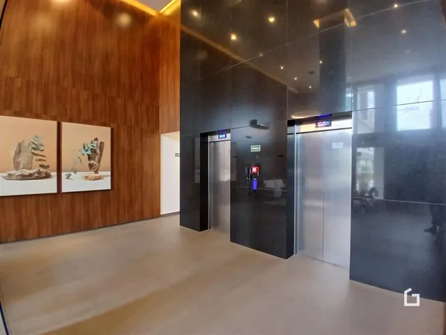 Hall de entrada moderno com revestimento de madeira e elevadores de aço inoxidável.
