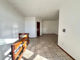 Hall de entrada com piso de cerâmica e corrimão de madeira em um imóvel.