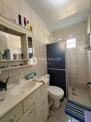 Foto de um banheiro com azulejos brancos e louças sanitárias.