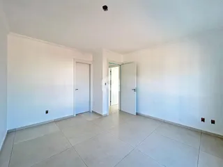 Vista interna de um corredor com paredes brancas e piso de cerâmica.