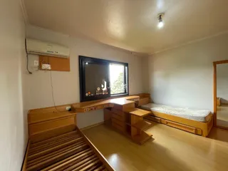 Quarto com piso de madeira e cabeceira de madeira em um imóvel no Brasil.