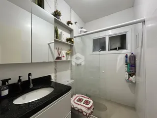 Banheiro moderno com revestimento branco e bancada escura.