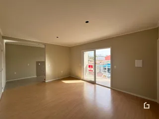 Ambiente interno de uma sala ampla com piso de madeira clara.