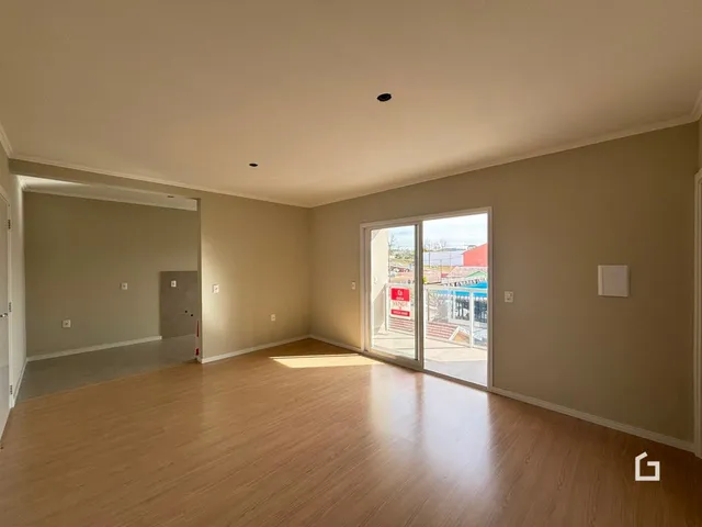 Ambiente interno de uma sala ampla com piso de madeira clara.