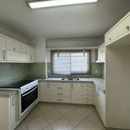 Foto de uma cozinha com armários brancos e piso de cerâmica.