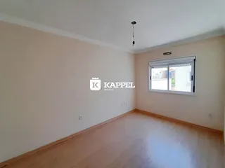 Foto de um cômodo vazio com paredes claras e piso de madeira.