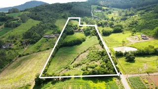 Vista aérea de uma propriedade rural com colinas verdes e áreas de vegetação.