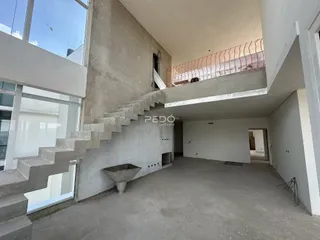 Vista interna de um espaço com paredes de concreto e escadaria em uma residência.