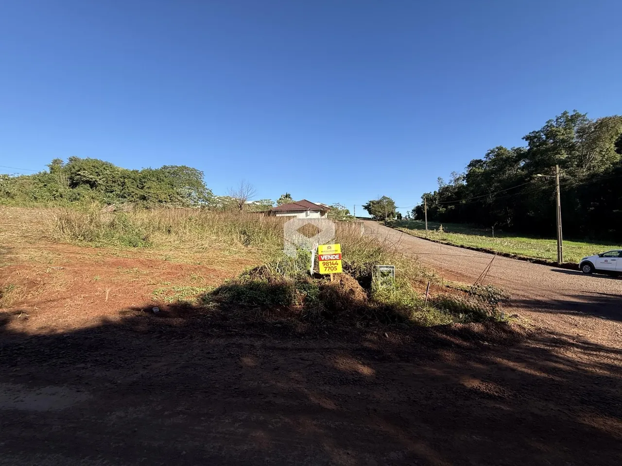 Vista externa de uma propriedade rural com estrada de terra.